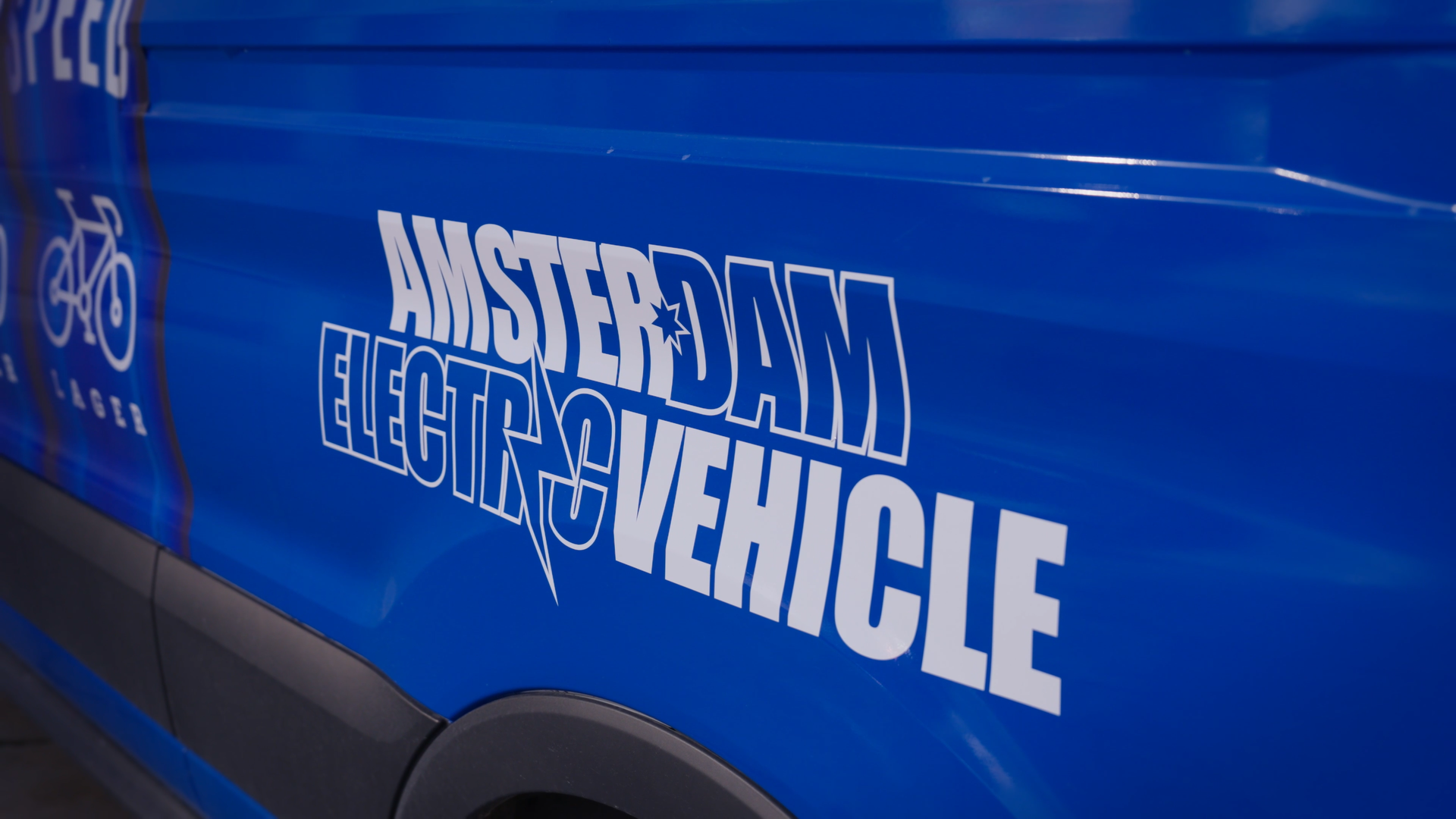 Close-up of a blue vehicle with 'Amsterdam Electric Vehicle' branding.