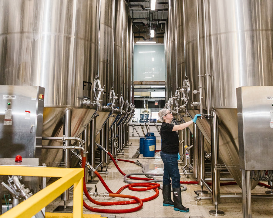 Person inspecting large stainless steel tanks in a industrial setting