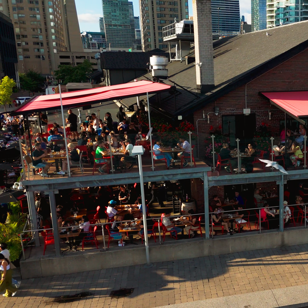 Outdoor seating area with people at a restaurant named 'Amsterdam' in an urban setting.