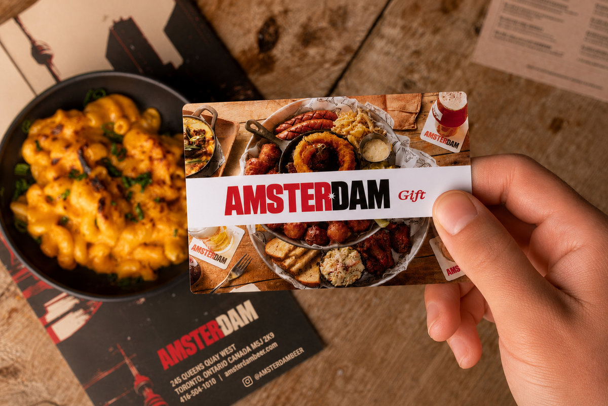 Hand holding a 'Amsterdam Gift' card with food images on a wooden surface.